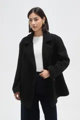 Chaqueta de corte holgado en color negro, con cuello solapa, cierre frontal con botones y bolsillos laterales.