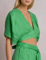 Blusa corta cruzada de lino verde, con escote en V pronunciado, mangas cortas amplias estilo kimono y lazo para anudar en la espalda.