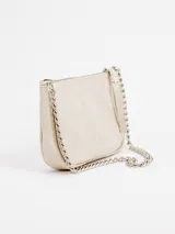 Cartera pequeña de cuero color beige, de diseño estructurado con base redondeada, cierre superior con tirador de cuero y correa de cadena metálica plateada.
