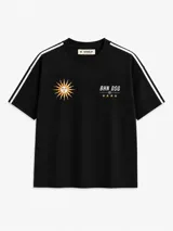 Remera negra de manga corta, con cuello redondo y diseño oversize. Presenta bandas blancas en los hombros y mangas, y detalles bordados en el frente: un sol estilizado y la inscripción 'BHN DSG' acompañada de estrellas.