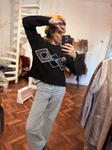 Sweater negro de tejido flexible con apliques geométricos metálicos bordados a mano.