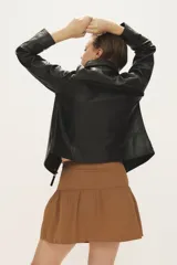 Campera de cuero negro al cuerpo, con cuello camisero, bolsillos de parche con solapa en el pecho y cierre frontal con broches a presión.