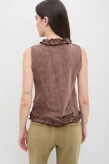Chaleco de terciopelo azul marino con efecto desgastado, presenta volados decorativos a lo largo del cierre frontal y en la cintura, con cuello alto y diseño ajustado.