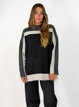 Sweater de punto con diseño color block en tonos gris oscuro, negro y gris claro. Presenta cuello alto, mangas largas y un corte holgado.