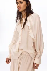 Blusa oversized de crepé en mezcla de viscosa y poliéster, color beige, con cuello redondo fruncido, escote en V con tirantes finos, mangas largas abullonadas con puños ajustados y volados decorativos en el frente.