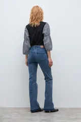 Jean de corte bootcut en color azul medio, con diseño de tiro medio y ruedo deshilachado.