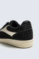 Zapatilla de estilo retro con cordones, confeccionada en una combinación de piezas de gamuza y material sintético. Presenta suela de goma a contraste y diseño de paneles laterales.