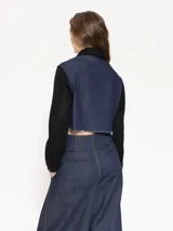 Campera corta de denim azul con mangas largas negras y cuello clásico negro.