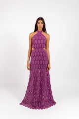 Vestido largo de encaje con patrón circular, color lila, de corte halter con tiras cruzadas al cuello y aberturas laterales en la cintura.