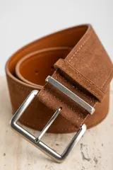 Cinto marrón de gamuza con hebilla metálica plateada.