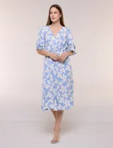 Vestido midi de calce holgado y caída fluida con escote en V cruzado, cintura elastizada fruncida y mangas cortas con volados superpuestos. Cuenta con un diseño estampado de flores grandes en tonos amarillo, blanco, azul marino y verde.