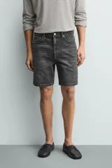 Bermuda de jean con corte regular fit, confeccionada en denim de algodón con elasticidad. Presenta diseño de cinco bolsillos, efecto lavado y cierre frontal con cremallera y botón.