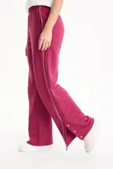 Pantalón deportivo negro de corte wide leg, sin frisa, con ribete blanco en los laterales y aberturas con botones en los tobillos.