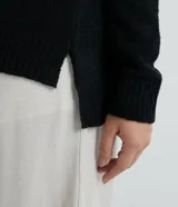 Suéter de punto texturizado con cuello redondo y mangas largas con sisa caída. Presenta un diseño liso y holgado, ideal para un estilo casual y versátil.