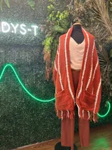 Pashmina tejida a mano en crochet, con diseño de rayas verticales en color crema y marrón. Presenta terminaciones con flecos en el ruedo y una textura acanalada distintiva.