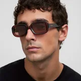 Lentes de sol con armazón grueso de policarbonato en tono bordó translúcido y diseño 3D redondeado. Poseen cristales polarizados de color marrón con protección UV400.