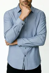 Camisa blanca de algodón, de diseño holgado y manga larga, con cuello camisero y cierre frontal de botones.