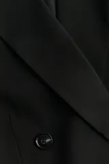 Blazer negro de doble botonadura con solapas de muesca, hombreras y bolsillos delanteros ribeteados con solapa.