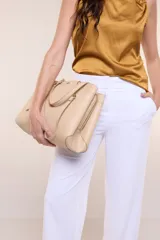 Cartera de hombro de cuero sintético beige, con estructura tripartita de compartimento central con cierre y dos compartimentos laterales con broche magnético. Posee asas dobles con detalles de cadena metálica dorada y un tarjetero independiente desmontable.
