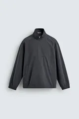 Sobrecamisa de corte regular confeccionada en mezcla de algodón y lyocell, con cuello alto y cierre frontal de cremallera. Presenta mangas largas con puños elásticos, bolsillos laterales de vivo y bajo ajustable con elástico en los laterales.