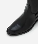 Bota de caña corta color negro, de PU (cuero sintético), con taco bloque bajo, punta levemente redondeada y dos tiras con hebillas metálicas en el lateral.