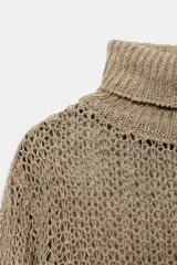 Jersey de punto calado color beige, con cuello alto vuelto y manga larga, confeccionado en lino.