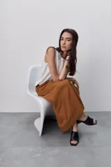 Falda larga color tostado, de línea evasé y silueta amplia, con diseño de paneles y costuras visibles pespunteadas.