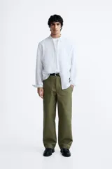 Camisa celeste a rayas verticales, de corte relaxed fit, confeccionada en lino y algodón. Tiene cuello abotonado, manga larga con puños abotonados, bolsillo de parche en el pecho y cierre frontal con botones.