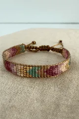 Pulsera tejida con cuentas Miyuki en tonos pastel, con diseño geométrico en colores verde, rosa, beige y dorado. Cuenta con un sistema de cierre ajustable mediante cordón marrón.