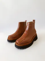 Botas cortas de cuero color marrón con elástico en los laterales y detalle de cuero texturizado en la parte delantera.