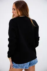 Sweater de punto acanalado en color negro, con cuello redondo y mangas largas. Presenta un diseño de corte recto y textura acanalada vertical.