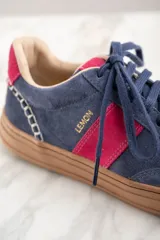 Zapatillas de gamuza azul con detalles en fucsia y suela marrón.