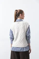 Chaleco de punto color bordó, con diseño de rombos y trenzas en relieve. Escote en V con ribete blanco y rojo.