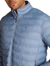 Campera acolchada Tommy Hilfiger color celeste, repelente al agua, con cuello alto, cierre de cremallera, dos bolsillos laterales con cremallera, logo de Tommy Hilfiger bordado en el pecho y diseño plegable.