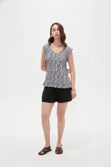 Blusa de poliéster sin mangas con cuello redondo y estampado geométrico en tonos marrones y blancos, de corte holgado y diseño fluido.