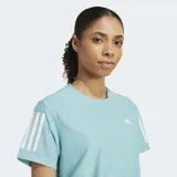 Remera de running Adidas de manga corta, color celeste claro, con cuello redondo. Presenta las tres franjas características de Adidas en blanco en las mangas y el logo de la marca en blanco en el pecho.
