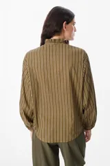 Camisa de manga larga con estampado de rayas verticales en color bordó y blanco. Presenta un cuello alto con volados y cierre frontal con botones a tono.