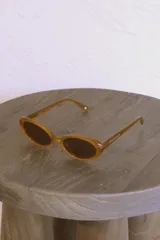 Lentes de sol color caramelo con forma ovalada y patillas con el logo de la marca Urban Haus.