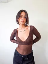 Body de manga larga confeccionado en microtul color marrón con detalle de strass plateado distribuido en toda la prenda. Presenta escote en V profundo y cierre inferior con broches.