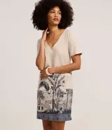 Vestido corto tipo t-shirt color beige, confeccionado en viscolino, con escote en V y mangas cortas. Presenta una estampa de arco de lapa en la falda.