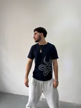 Remera de algodón color azul marino con estampa serigráfica en color gris claro en el lateral inferior. Presenta cuello redondo reforzado y corte regular.