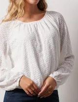 Blusa blanca texturizada, marca Harper, de manga larga con terminación fruncida y ruedo con frunce. Tiene forro interno a tono.