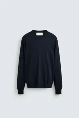 Jersey de punto color azul marino, con cuello redondo y manga larga. Presenta acabados en rib en cuello, puños y bajo.