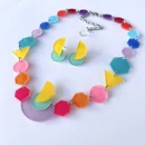 Conjunto de collar y caravanas con formas geométricas de acrílico en colores pastel. El collar tiene una cadena plateada ajustable.