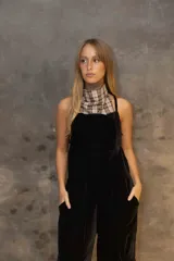 Enterito de terciopelo negro con diseño de pierna ancha y bolsillos laterales tipo cargo. Presenta espalda descubierta con tiras ajustables y bordado decorativo en la parte trasera.