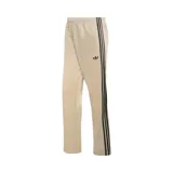 Pantalón de jogging Adidas de corte regular en color beige, con las tres tiras características en negro a lo largo de los laterales y el logo del trifolio bordado en la parte frontal.