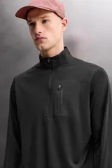 Sudadera técnica color vino tinto, de manga larga, con cuello subido y cierre frontal de cremallera. Presenta un bolsillo frontal con cierre de cremallera oculta en costura y detalle de logo estampado. El tejido tiene estructura waffle en el interior.