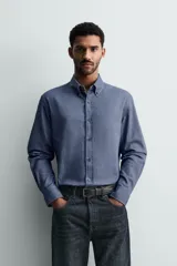 Camisa de corte regular fit confeccionada en tejido de algodón con efecto lavado. Presenta cuello abotonado, manga larga con puños abotonados, bolsillo en el pecho y cierre frontal con botones.