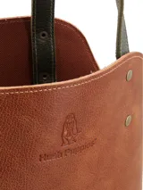 Matera de cuero con diseño bicolor en tonos marrón y verde oliva, con correas largas para hombro y detalles de remaches metálicos. Incluye logo de la marca grabado en el frente.
