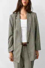 Blazer marrón de cuello solapa con muescas, manga larga y bolsillos de vivo con solapa. Cierre frontal con un botón.